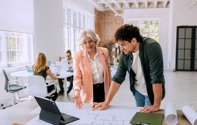 Two people standing and looking at a laptop