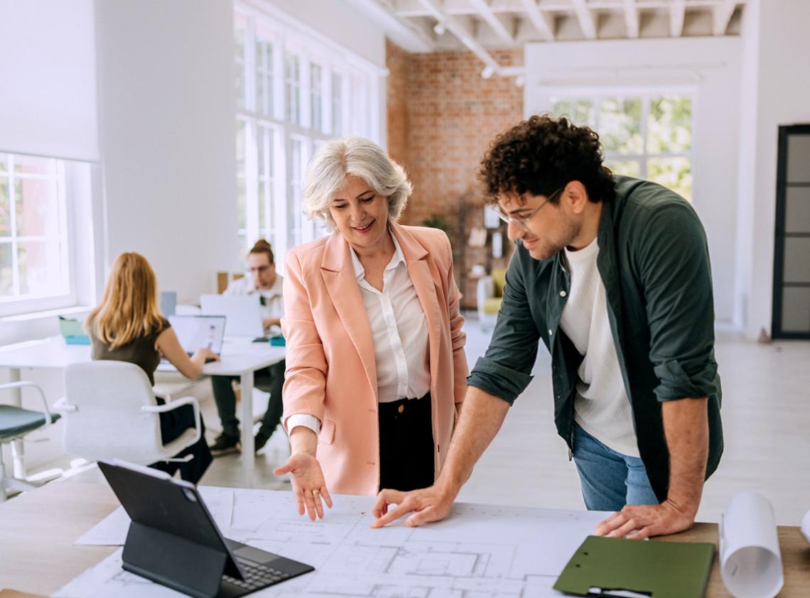 Two people standing and looking at a laptop
