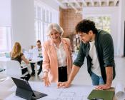Two people standing and looking at a laptop