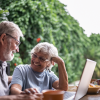 Senior couple smiling as they sit outside in their backyard