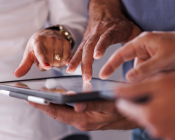 Three different hands pointing at an ipad screen