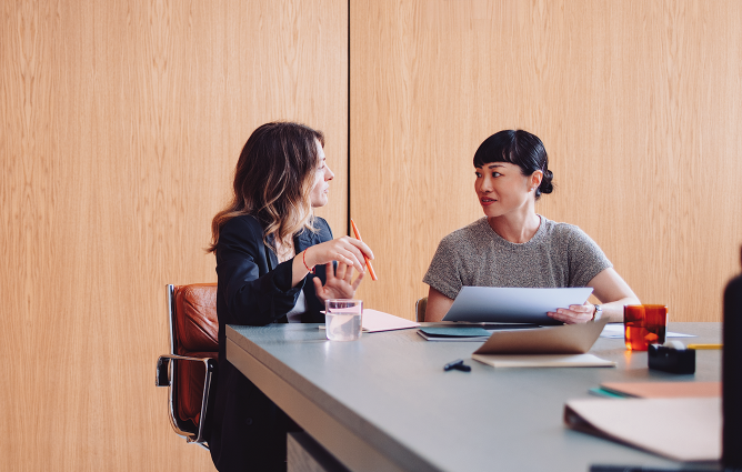 Two females discussing at a table