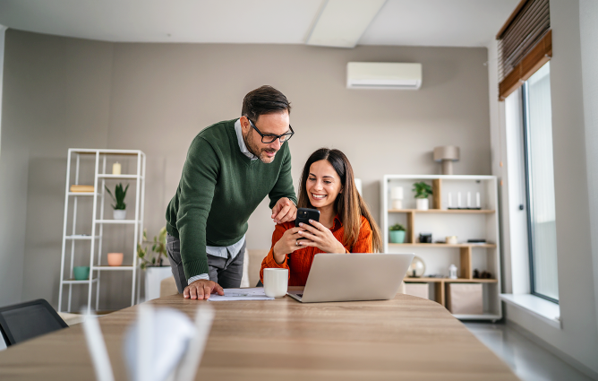 A couple reviewing information on their laptop on their kitchen table