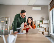 A couple reviewing information on their laptop on their kitchen table